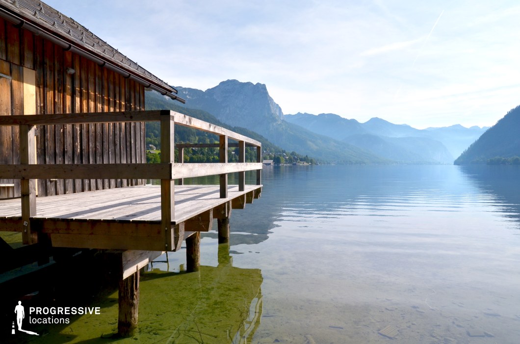This peaceful location showcases a weathered wooden deck extending over clear, shallow water, framed by a vast alpine lake and layers of softly silhouetted mountains in the distance. The open composition and minimal elements create a sense of space, calm, and introspection. The smooth surface of the lake and the natural timber textures enhance the serene atmosphere. Ideal for romantic films, travel sequences, or reflective scenes, this setting suits stories of emotional turning points, reunions, or meditative solitude in nature.