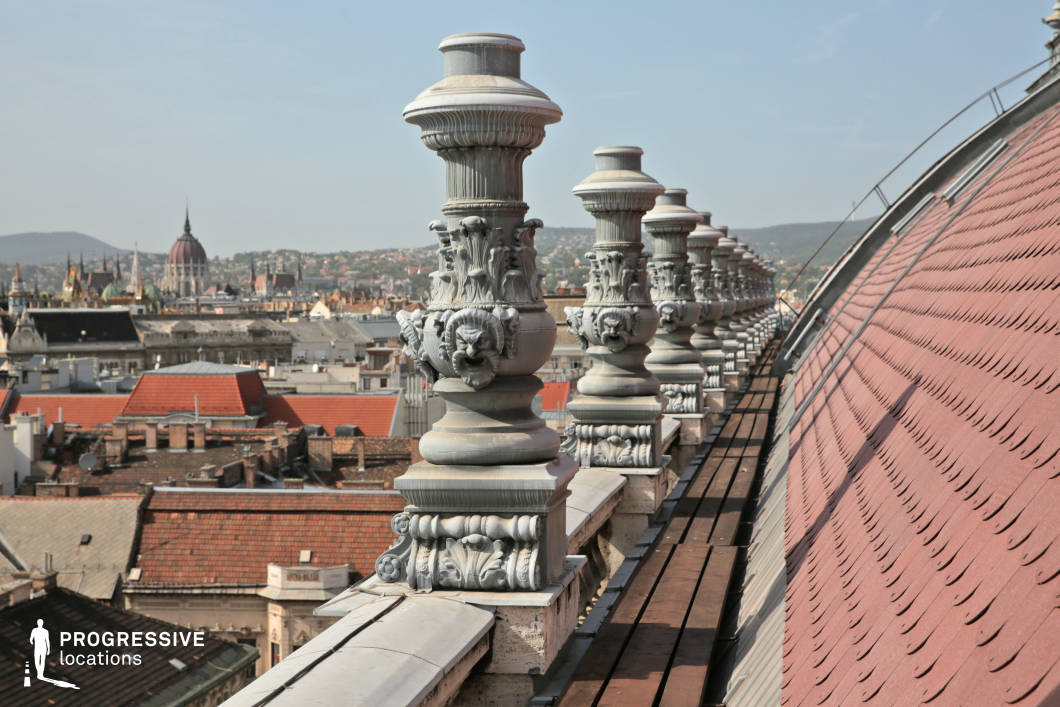 This image presents a stunning view of an ornate balustrade atop a historical building, adorned with intricate sculptural details. Each post is finely carved with floral patterns and faces, lending the scene a classical and artistic quality. In the background, the dome of the basilica rises prominently, providing a striking contrast to the detailed balustrade. Below, the city's rooftops create a textured expanse, with a mix of traditional tiles and diverse architectural elements. The fine craftsmanship of the balustrade is highlighted, with the basilica adding a regal focal point to the composition. This location is ideal for capturing the combination of historical and decorative architecture, making it a perfect setting for architectural photography or urban-focused projects.
