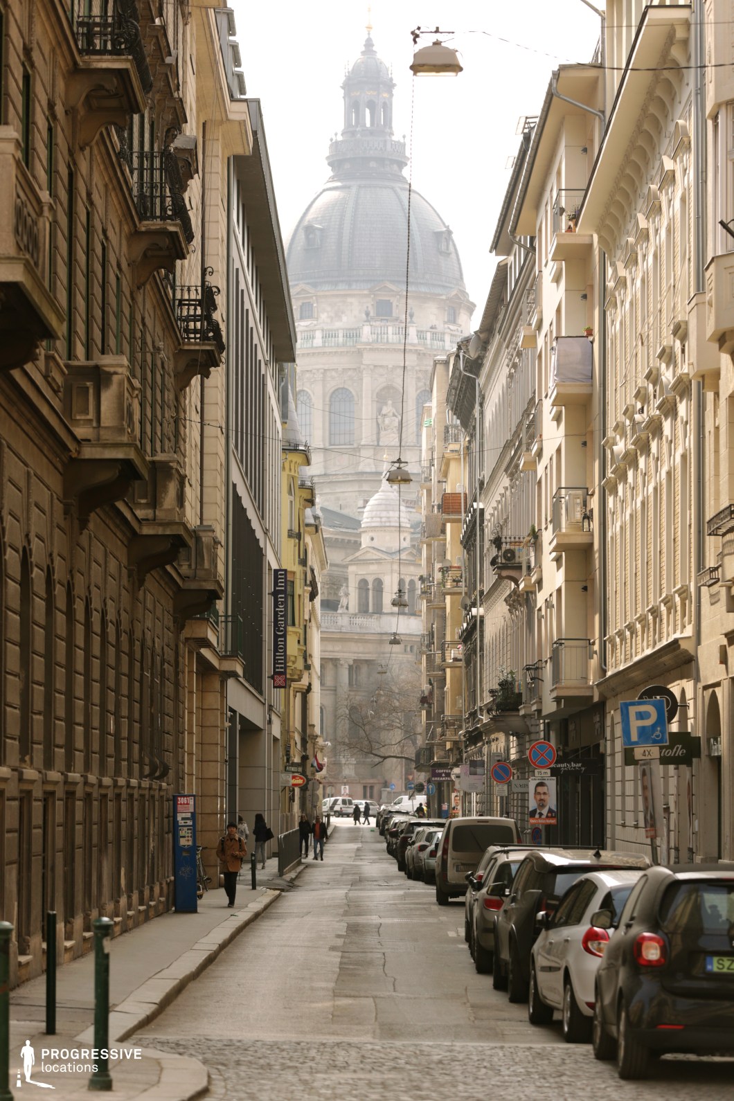 This is a picturesque European street leading to a magnificent cathedral with a prominent dome, creating a striking focal point. 