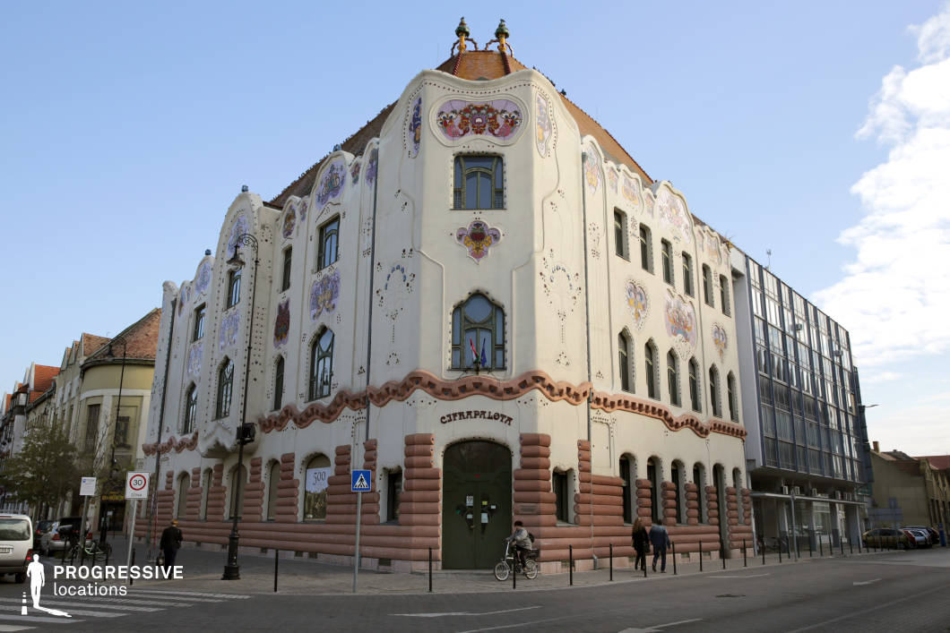 This image features a striking Art Nouveau building with a richly decorated facade, characterized by flowing curves, intricate floral motifs, and colorful ceramic embellishments. The asymmetrical design, wavy architectural lines, and whimsical details give the structure a fairy-tale quality. The pastel hues contrast beautifully with the bold, rounded brickwork at the base, adding depth and texture. The building’s ornate roof, adorned with small towers and decorative elements, enhances its distinctively playful yet elegant appearance. This location is ideal for filming historical period pieces, fantasy narratives, or artistic dramas, offering a visually captivating backdrop that evokes themes of creativity, cultural heritage, and architectural splendor.
