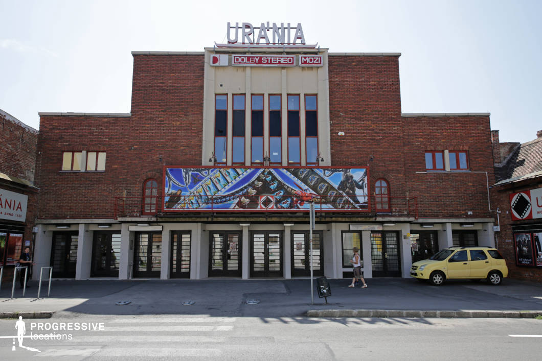 This image captures a historic cinema building with a bold brick facade and a mid-century modern design. The lower level is characterized by a row of glass entrance doors framed by concrete pillars, evoking the charm of classic movie theaters. The aged brickwork and utilitarian design contribute to a nostalgic, old-school urban atmosphere. This location is ideal for filming retro-themed stories, independent dramas, or urban cultural narratives, providing a visually distinctive setting that highlights themes of nostalgia, cinematic history, and community entertainment.