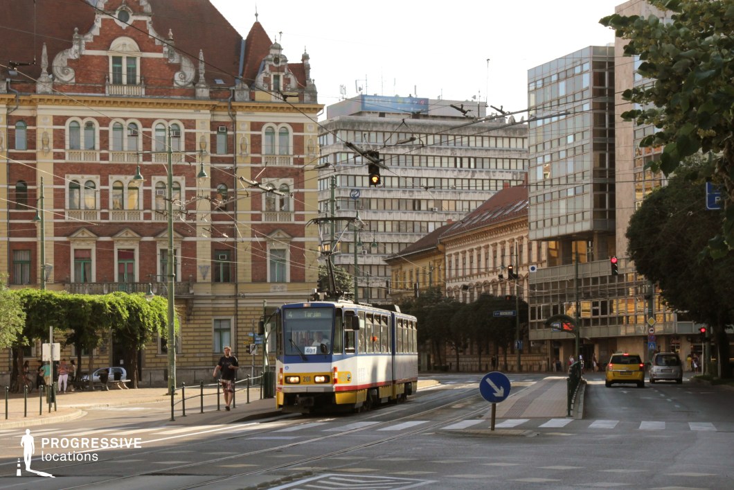 This location features a dynamic blend of architectural styles, from ornate historic façades with decorative masonry to modernist office blocks with glass and concrete lines. A tram navigates the center of the street, surrounded by overhead power cables and framed by intersecting roads, enhancing the urban atmosphere. The juxtaposition of old and new elements creates visual interest and depth, while the functional street layout adds realism to any scene. This location is well-suited for contemporary dramas, urban documentaries, European political thrillers, or time-travel narratives. It provides a vivid backdrop for public transport scenes, character arrivals, or urban lifestyle montages.