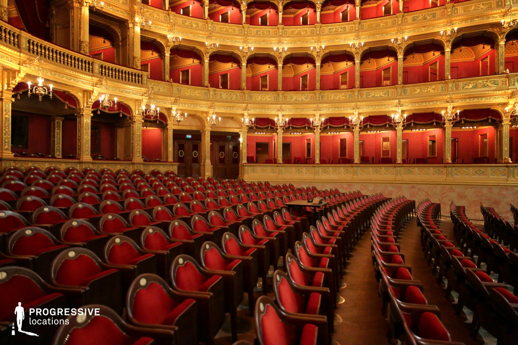 This luxurious opera house auditorium exudes elegance with its meticulously arranged red velvet seats, framed by golden accents and intricate architectural details. The balconies, adorned with gilded moldings and deep red drapery, create a regal ambiance, enhanced by the glow of classical chandeliers. The sweeping, curved seating arrangement offers an immersive perspective, perfect for theatrical performances, cinematic productions, or high-end event settings. The hall’s historic charm, combined with its sophisticated layout, makes it an iconic backdrop for grand cultural and artistic showcases.