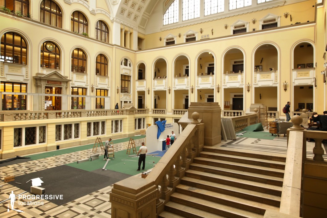 This grand neoclassical atrium features soaring arched windows, intricate moldings, and a spacious open floor plan, creating an atmosphere of elegance and prestige. A grand staircase with a stone balustrade leads to an upper gallery, while large arched balconies overlook the central space. The symmetrical layout, classical architectural details, and warm cream-colored tones enhance the historic and institutional character. With its mix of open space and elevated walkways, this location is ideal for academic, cultural, or formal institutional settings requiring a refined and monumental ambiance.