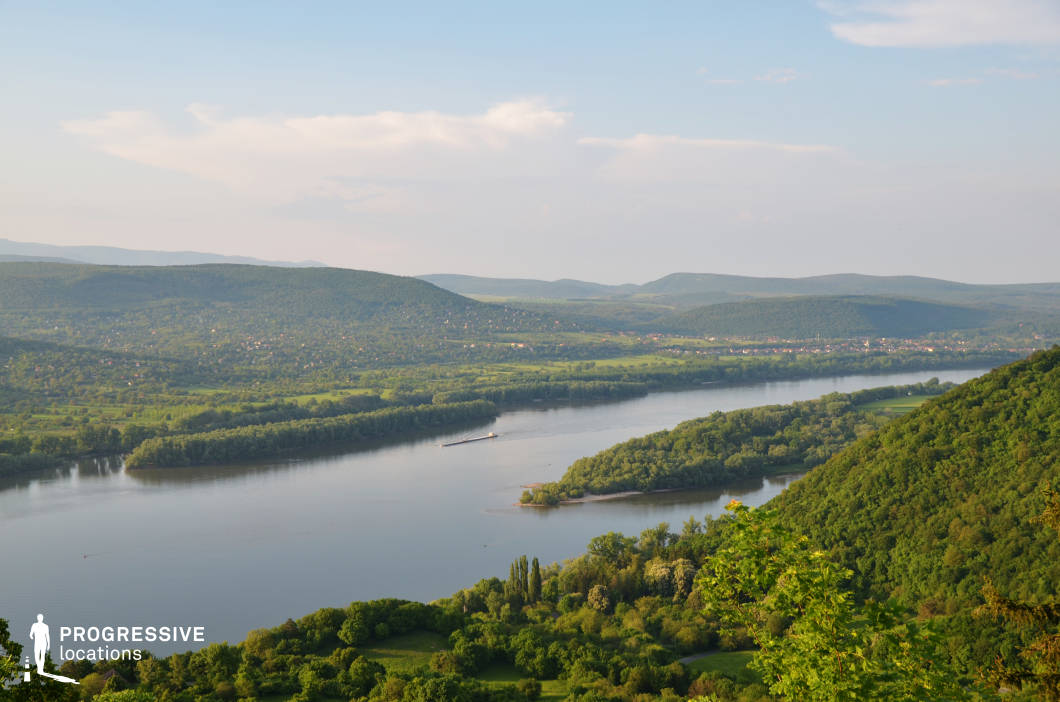 This wide-angle view captures a sweeping river as it curves through a lush, layered landscape of rolling hills and expansive valleys. The scene is marked by vibrant greenery, smooth water surfaces, and distant ridgelines that create natural depth and cinematic grandeur. The composition’s harmony and scale make it ideal for establishing shots in adventure films, historical epics, or romantic dramas, particularly for sequences involving travel, reflection, or a return to nature in a story’s turning point.