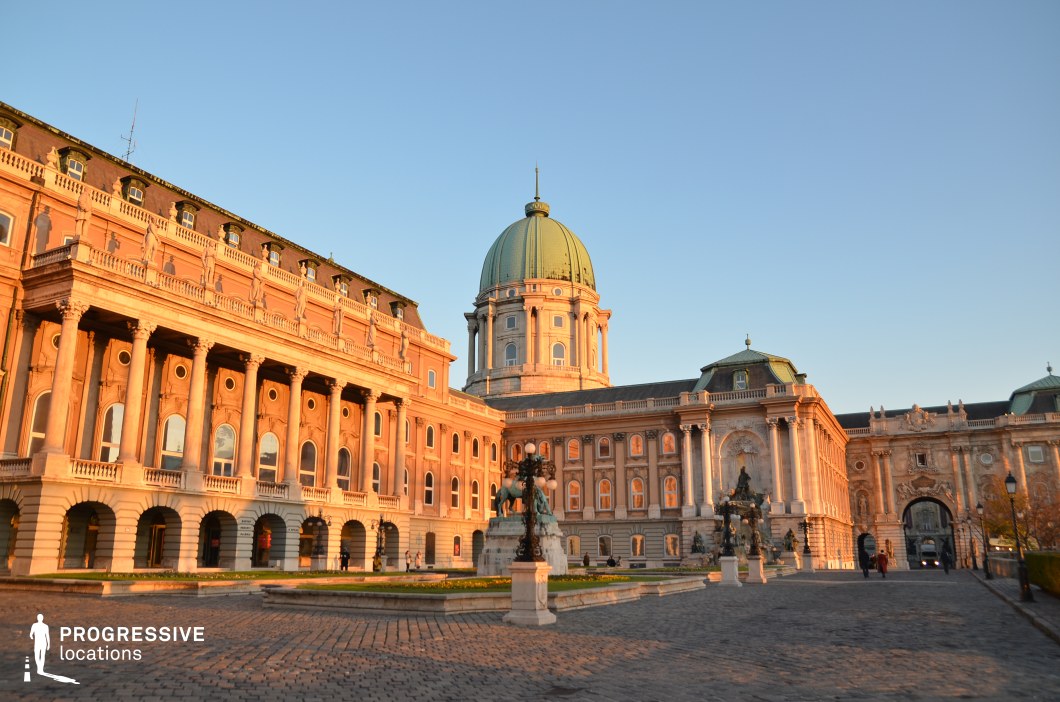 This grand palace complex features a stately neoclassical design, highlighted by a large domed central structure flanked by symmetrical wings adorned with ornate sculptures, decorative columns, and arched windows. The expansive cobblestone courtyard is framed by elegant balustrades, historical fountains, and detailed stonework, reinforcing the location's aristocratic and imperial character. The monumental scale and architectural richness make this an ideal setting for historical dramas, regal narratives, or period epics, providing a backdrop suited for royal ceremonies, political intrigue, and grand processional scenes.