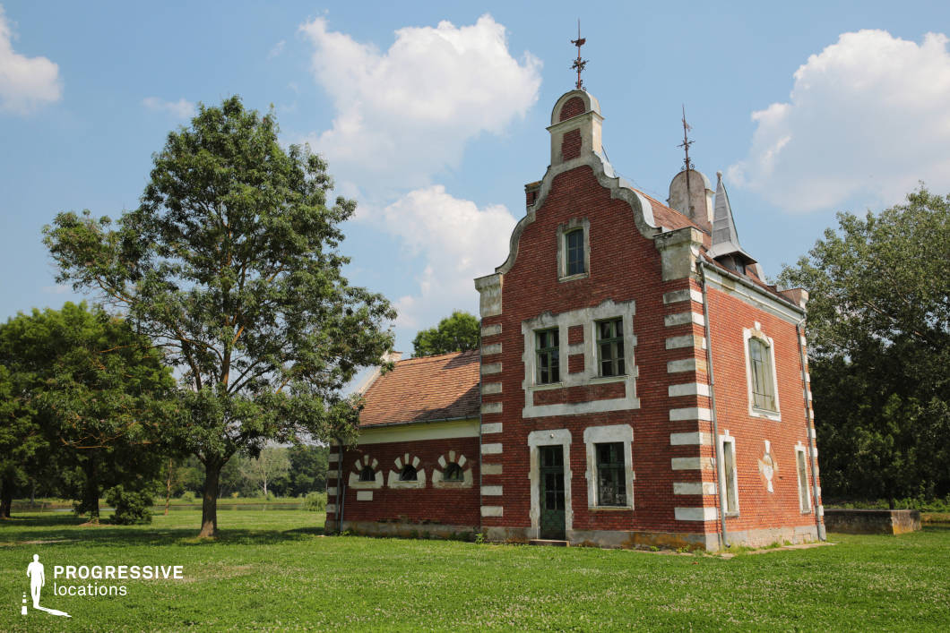 This image features a distinctive Dutch-style brick house with a stepped gable, contrasting white stone accents, and weathered architectural details. The red brick façade, arched windows, and decorative rooftop elements contribute to its historic charm, while the surrounding open meadow enhances its secluded and rural character. The aged yet elegant appearance of the building, combined with its unique European influence, makes it an ideal filming location for historical narratives, period dramas, or mystery films, offering a visually compelling and atmospheric backdrop for a variety of storytelling genres.