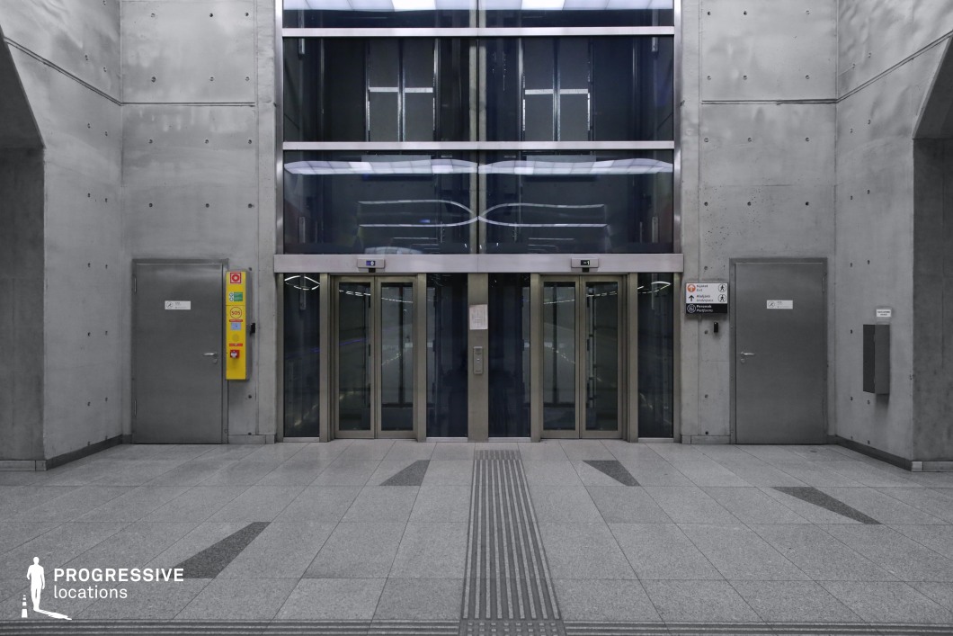 This image showcases a modern elevator bank with glass and metallic doors set against smooth concrete walls, featuring a minimalist, industrial design. The space is enhanced by bright, even lighting and geometric flooring patterns, creating a sleek, contemporary atmosphere. The contrast between reflective glass and solid concrete adds structure and openness, making it a versatile location for urban-themed scenes. This location is ideal for modern, futuristic, or industrial films, such as thrillers, sci-fi, or action movies.