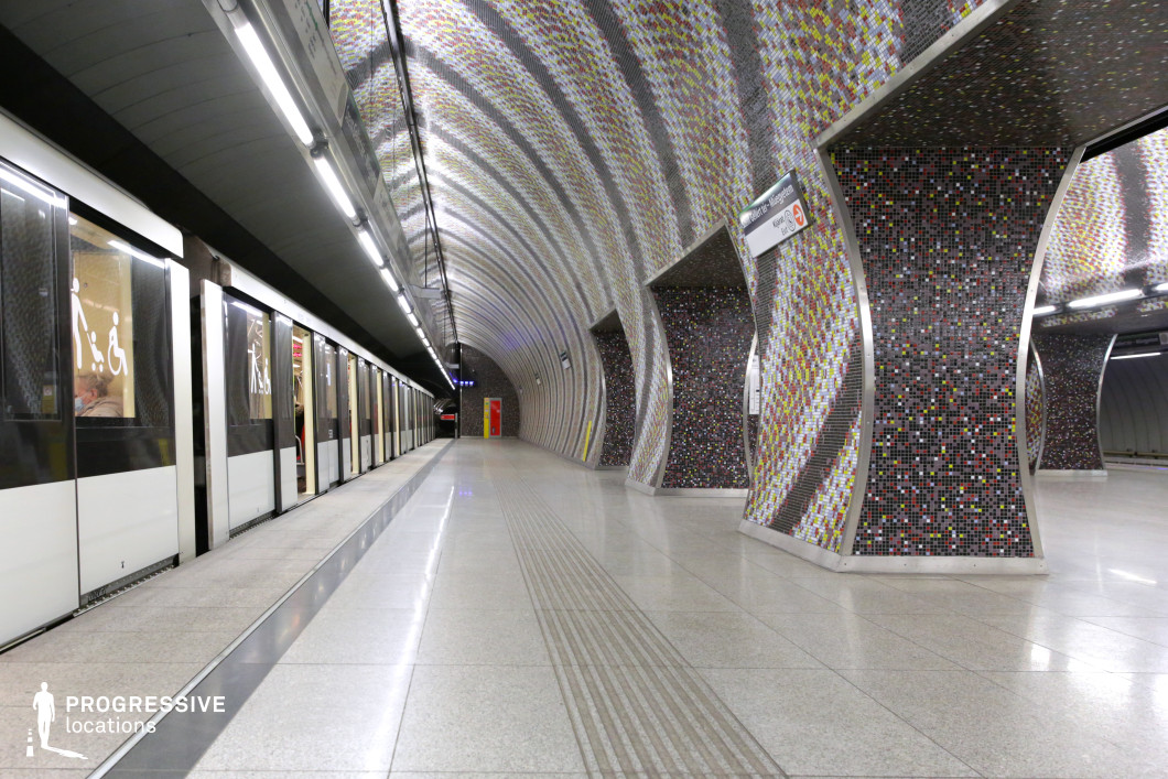 This metro station features a striking tunnel-like design with undulating, mosaic-tiled walls and ceiling, creating a visually dynamic and immersive space. The small, multicolored tiles form intricate patterns that reflect light, enhancing the curved structure’s depth and texture. The polished flooring adds to the sleek, modern aesthetic, while the long, continuous perspective of the platform emphasizes movement and symmetry. The combination of geometric curves, reflective surfaces, and artistic detailing makes this location ideal for filming sci-fi, retro-futuristic, or artistic productions, offering a visually engaging and architecturally unique setting.