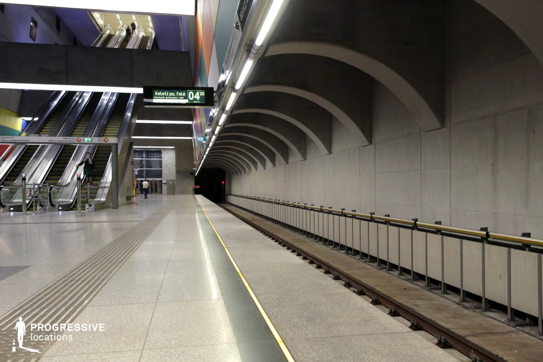 This image features a minimalist subway platform with industrial concrete walls, arched ceilings, and metallic railings along the tracks. The clean lines and bright, evenly distributed lighting create a modern, utilitarian atmosphere. The escalators in the background add movement and direction to the space, making it ideal for futuristic or urban settings. This location is perfect for thrillers, action films, or science fiction, offering a versatile space for dynamic shots and dramatic sequences.