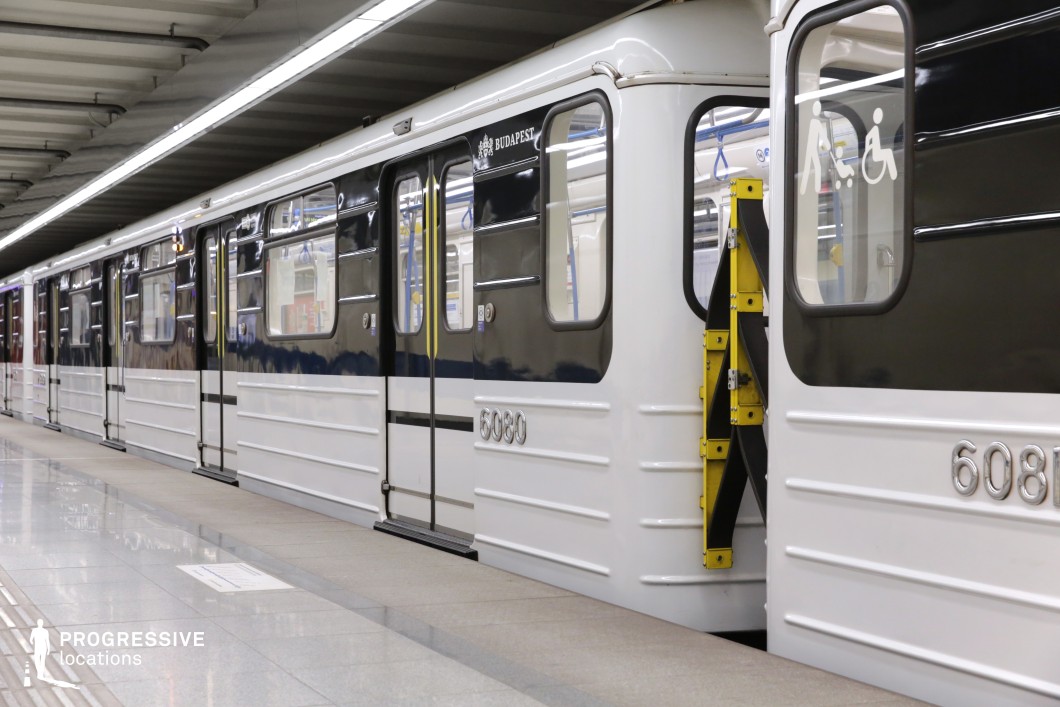 This image captures a close-up view of a modern subway train with black and white cars. The train is designed with a sleek, industrial look, with metallic finishes and clear door labeling. The clean, polished tiles of the platform reflect the train’s design, enhancing the minimalistic and modern ambiance of the space. The presence of the accessibility lift and functional elements like the clearly marked doors make this setting ideal for filming scenes that require an urban, modern transport environment, suitable for genres such as drama, action, or urban thrillers. The space’s architectural simplicity and functional details offer a versatile backdrop for various types of cinematic storytelling.