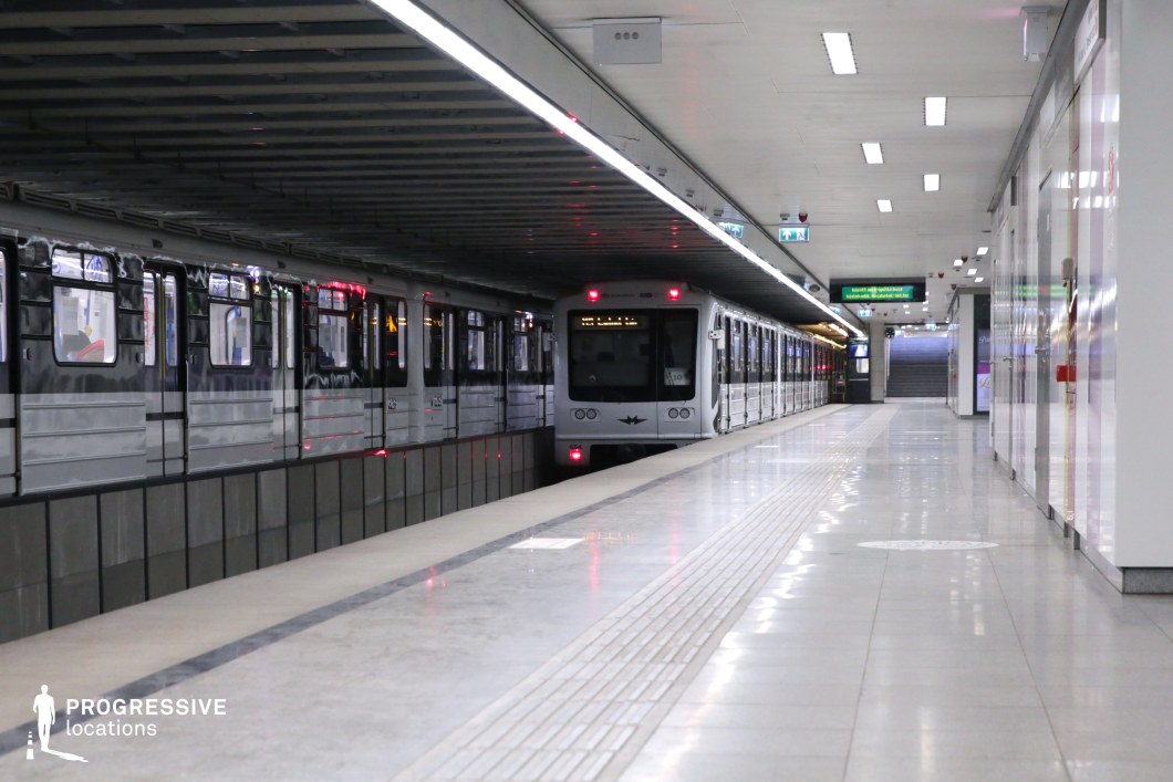 This image showcases a contemporary subway station with a sleek, minimalistic design. A modern subway train, featuring a black and silver exterior, is stationed on the platform, while the clean, polished floors reflect the train's design. The ceiling is lined with evenly spaced lights that contribute to the bright, industrial atmosphere of the station. The functional layout, with clear signage and wide walkways, ensures an efficient and spacious environment. This location is ideal for filming genres such as action, thriller, or urban dramas, offering a dynamic, modern backdrop that complements high-energy and dramatic scenes. The design's clean lines and symmetrical elements provide versatility for a variety of cinematic styles.