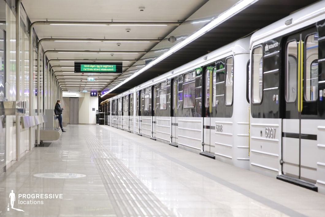 This image showcases a modern subway platform with sleek black and white subway cars along one side. The platform is spacious, with polished floors and linear patterns that create a sense of order. The ceiling features bright, linear overhead lighting, enhancing the contemporary urban atmosphere. Neon-colored signage adds a dynamic visual element, contrasting with the clean, minimalist design of the space. The area’s architectural elements, including the streamlined benches and uniform tile patterns, contribute to its modern, industrial feel. This location is ideal for filming genres like urban thrillers, action scenes, or even futuristic dramas, offering a visually striking and versatile backdrop for various cinematic styles.
