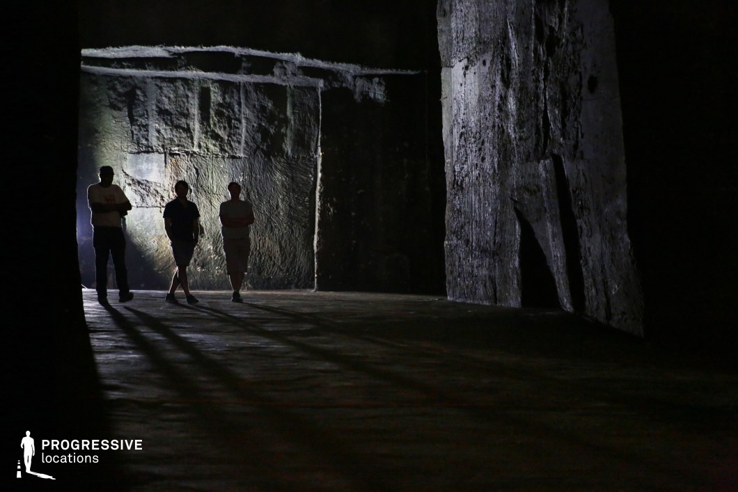 This vast underground stone quarry features imposing, rough-hewn rock walls and a cavernous atmosphere. The textured stone surfaces, marked by deep cuts and irregular formations, create a raw, industrial aesthetic, while the interplay of light and shadow enhances the sense of mystery and isolation. The dimly lit environment, accentuated by a single light source casting elongated shadows, adds to the dramatic tension. The setting is ideal for thriller, horror, and adventure productions, providing an immersive backdrop for hidden chambers, secret hideouts, or eerie underground explorations. Its expansive, rugged structure also makes it suitable for historical or post-apocalyptic storytelling.