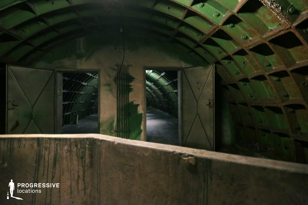 Metal tunnel with dual doors and green arches, a film and photography location featuring industrial symmetry.