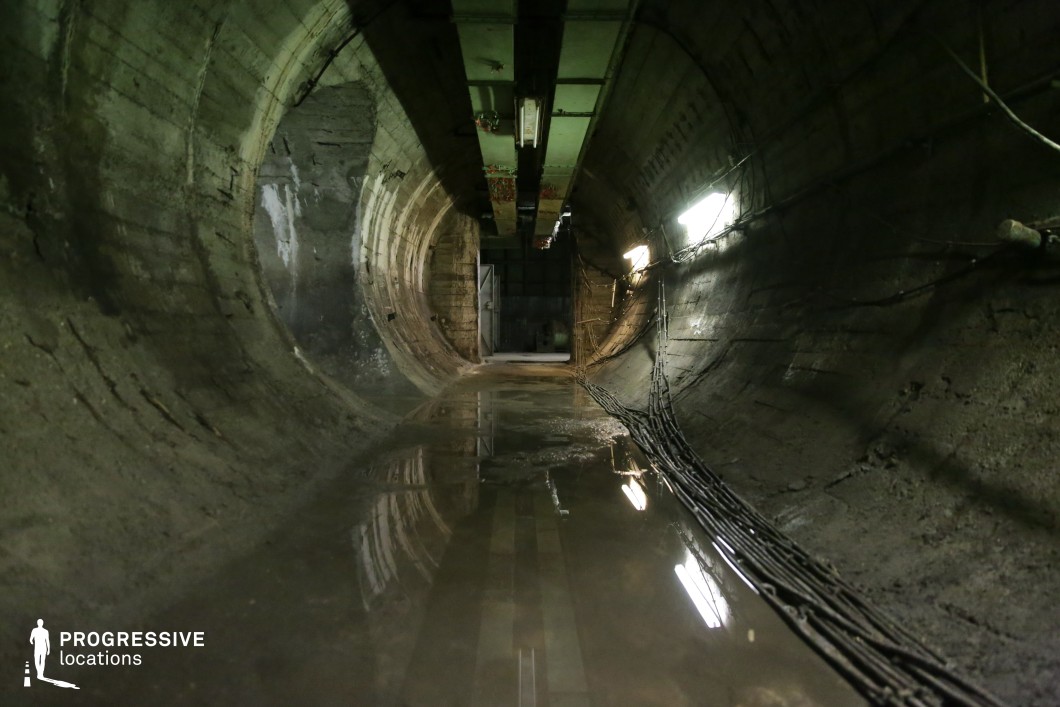 Flooded concrete tunnel with reflections and cables, available as a film and photography location.