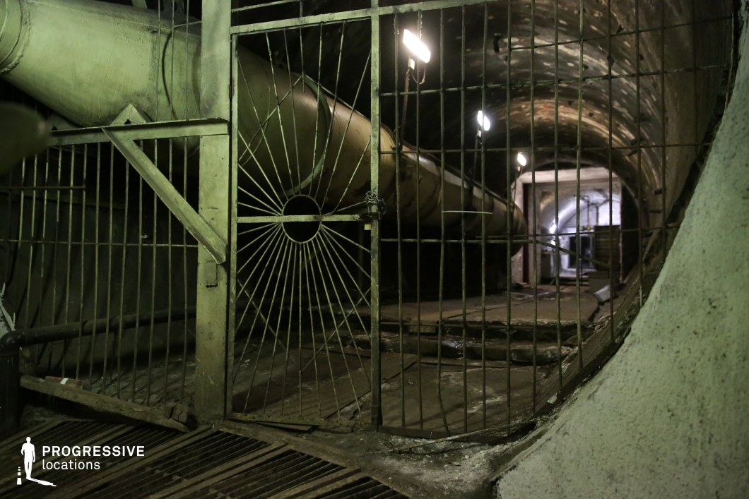 Underground tunnel with steel gate and pipes, an atmospheric film and photography location with industrial elements.