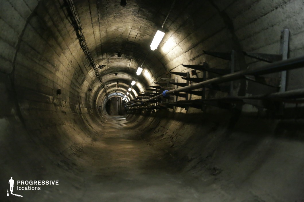 Narrow concrete tunnel with cables and lights, ideal underground film and photography location with industrial style.