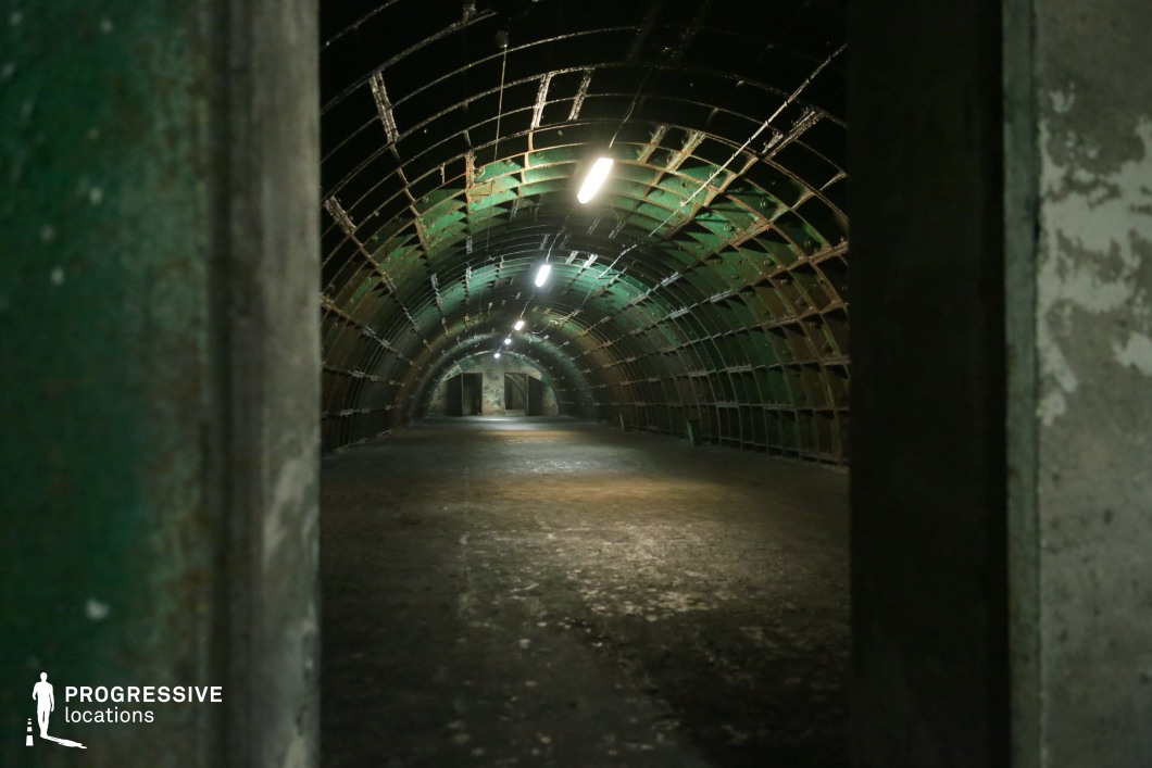 Arched green metal passage with concrete floor, ideal for photography and film shoots in industrial environments.