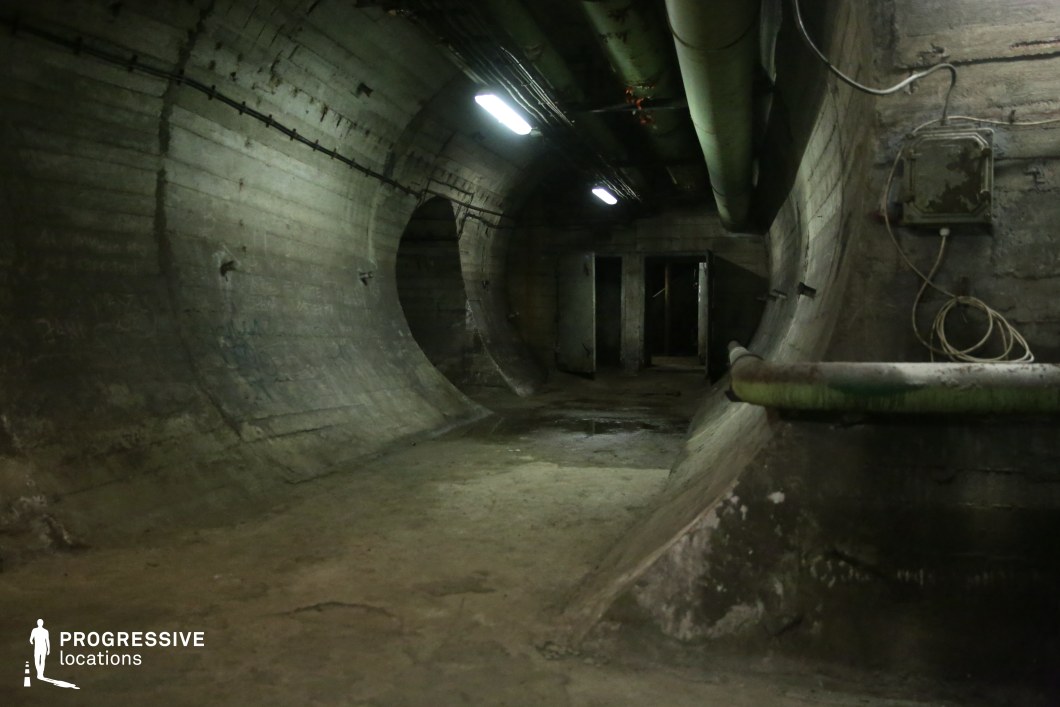 Wide concrete tunnel with pipes and wiring, used as an industrial film and photography location.