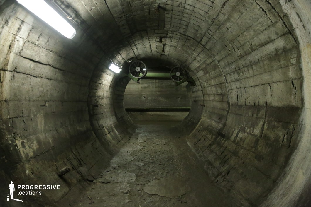 Cylindrical concrete tunnel with fans and lighting, a film and photography location with industrial depth.