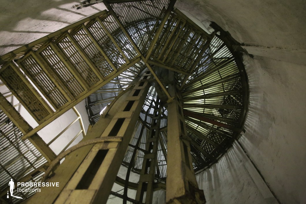 Industrial spiral stairwell with repeating grids, ideal film and photography location featuring vertical geometry.