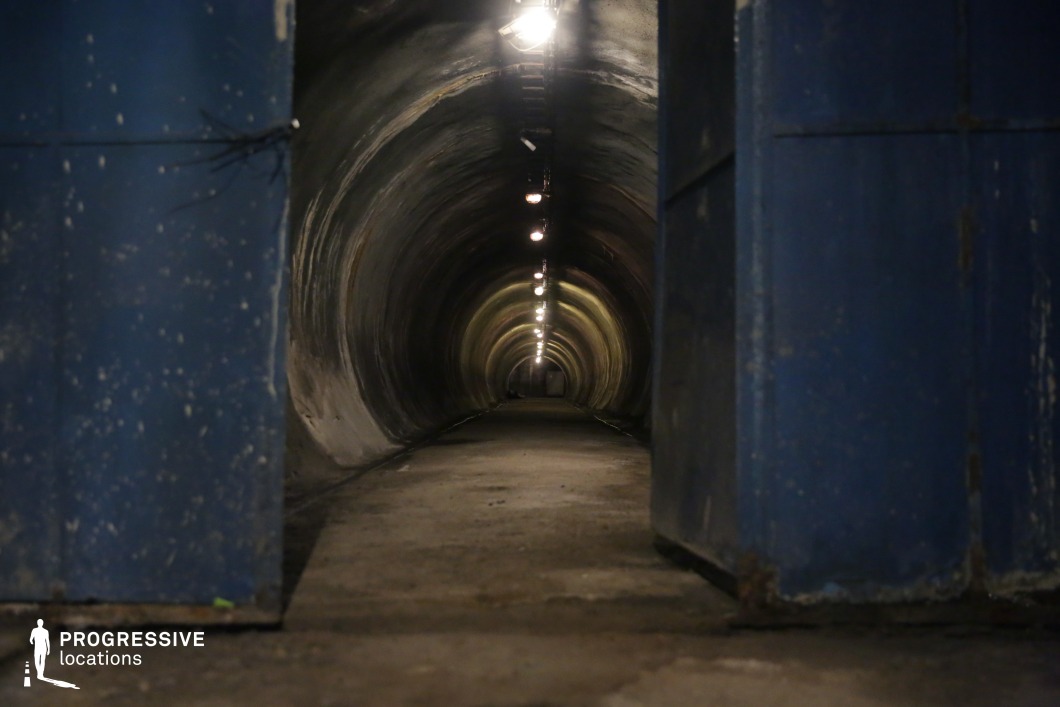 Concrete tunnel with blue metal doors, offering depth and symmetry as a film and photography location.