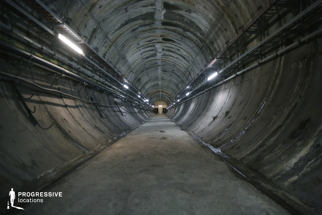 An industrial concrete tunnel with pipes and lights, ideal as a film and photography location with technical atmosphere.