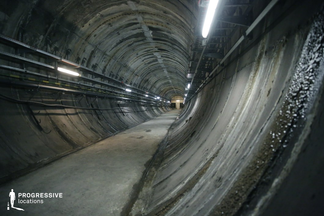 A curved concrete passage with industrial lighting, used as a film and photography location for technical scenes.