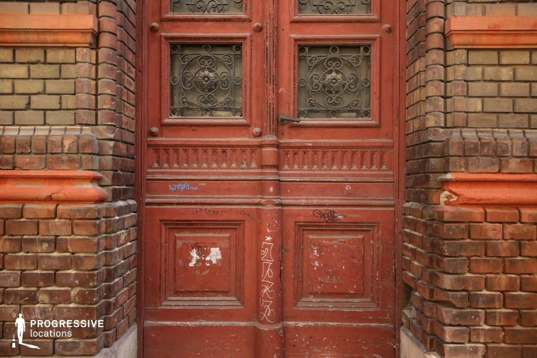 Aged red wooden door with brick frame, film and photography location highlighting texture and detailed surface elements