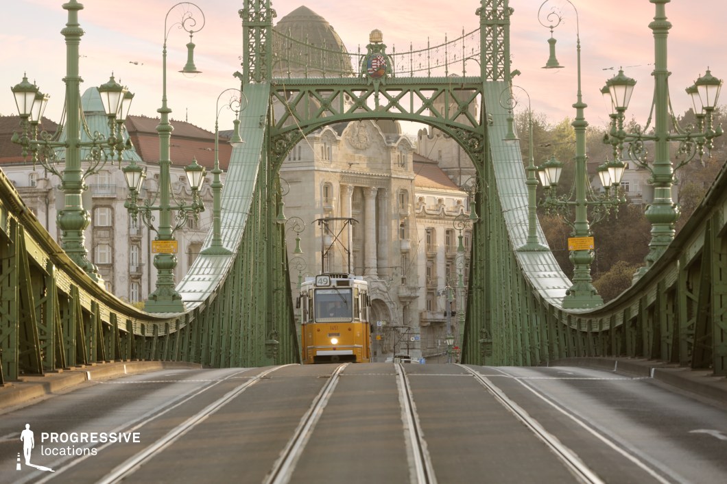 Symmetrical bridge arch with tram tracks and central vehicle forming a film and photography location with strong perspective