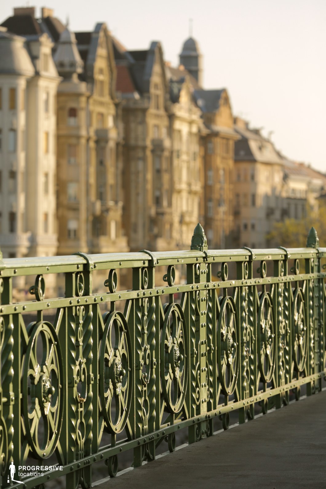 Ornate green bridge railing in close detail against urban buildings as a film and photography location