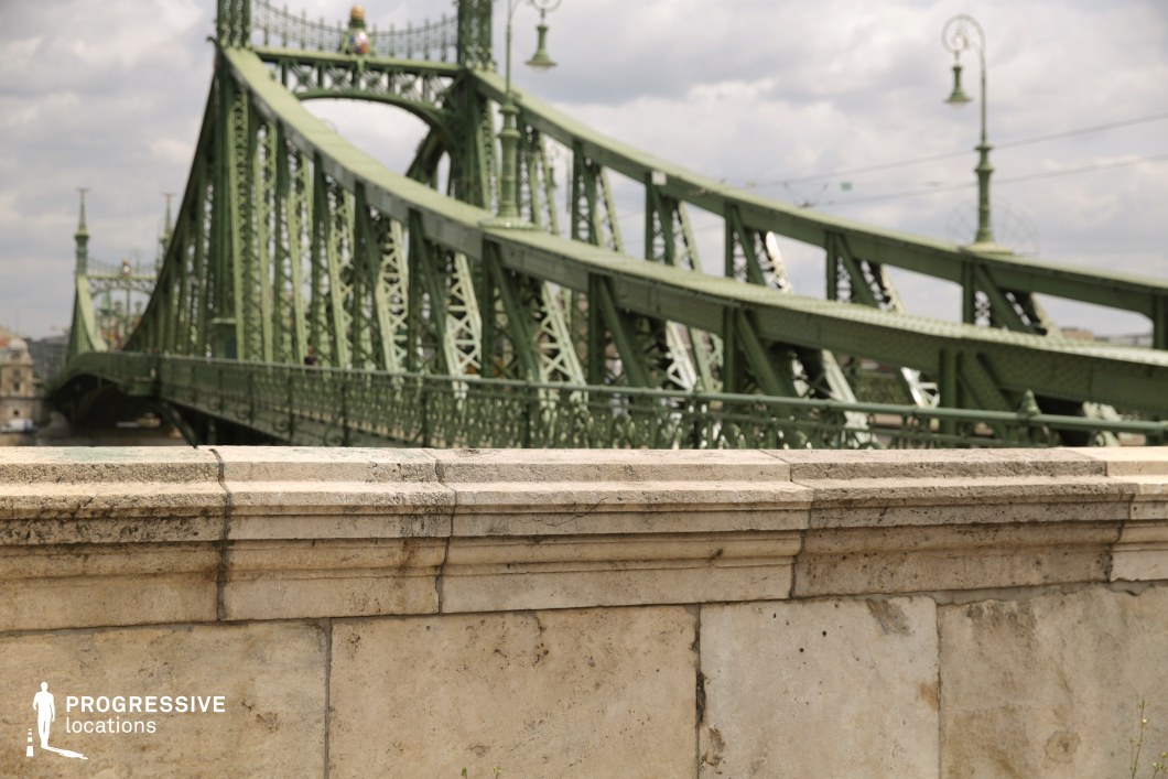 Stone wall foreground with green bridge structure behind as a photography and film location with layered composition