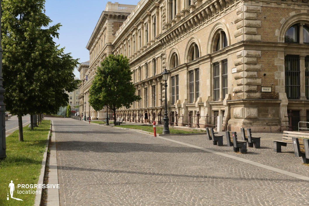 Cobblestone walkway beside historic buildings with trees and benches as a film and photography location