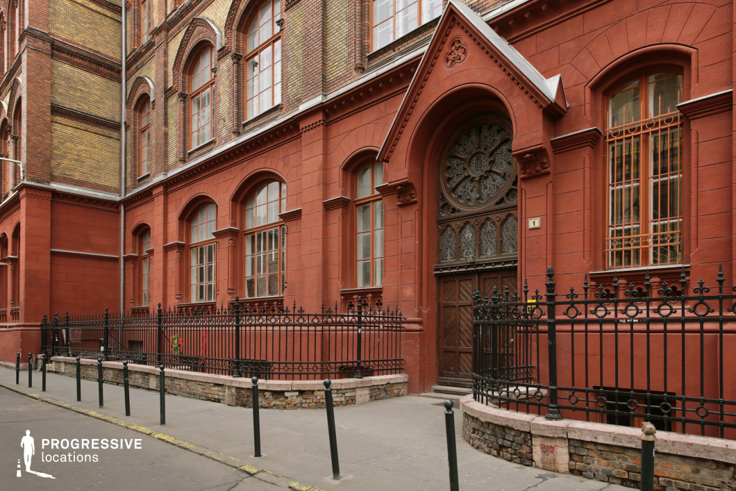 Red brick building with arched windows and iron fence as a photography and film location with strong facade detail