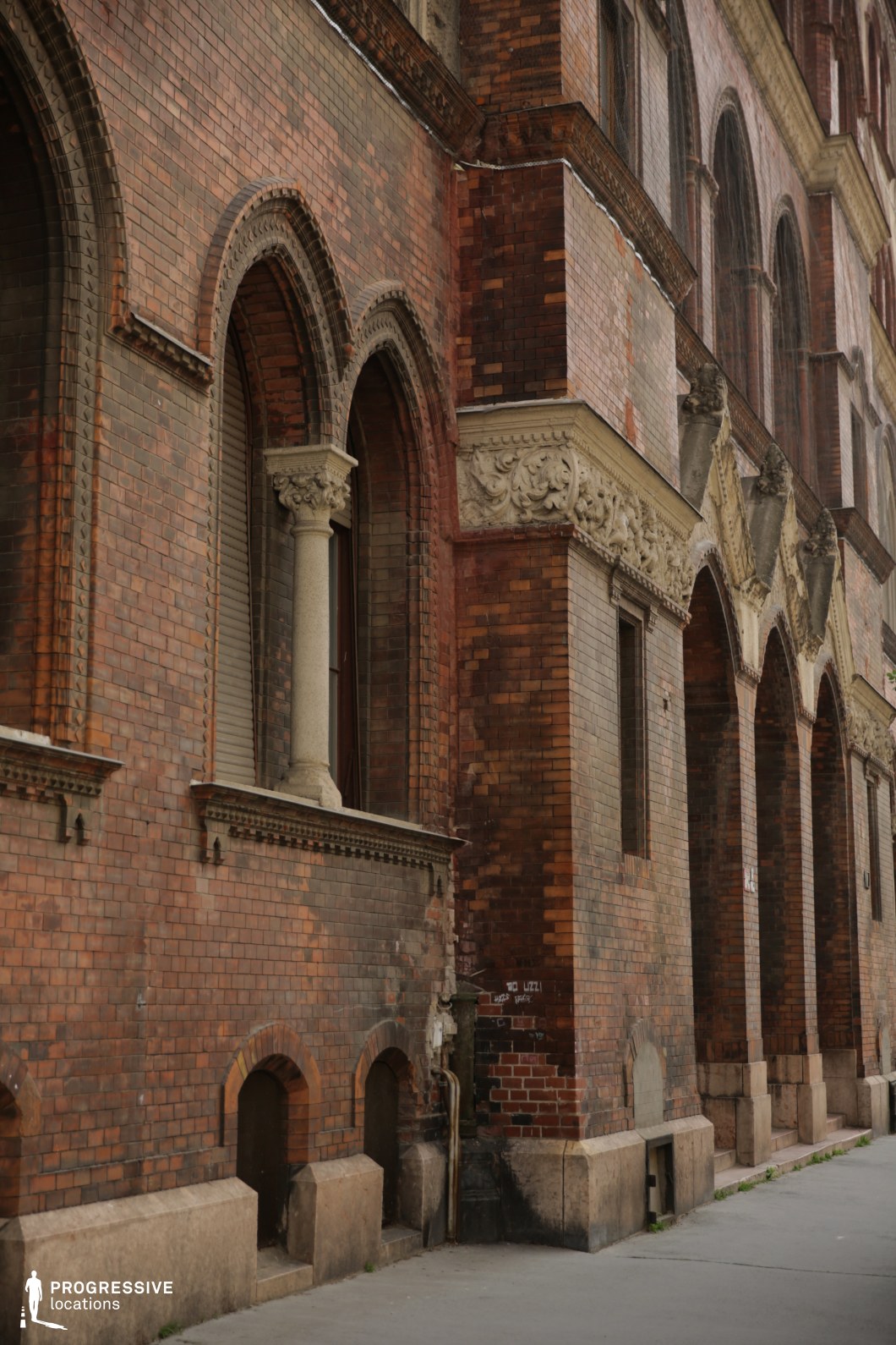 Historic brick facade with tall arched windows serves as a detailed film and photography location with strong vertical rhythm