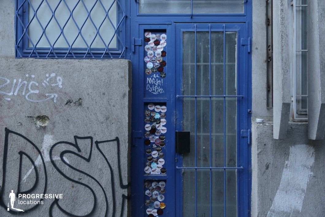 Blue metal door with barred window in concrete wall, available for filming or photo shoots with strong textural detail
