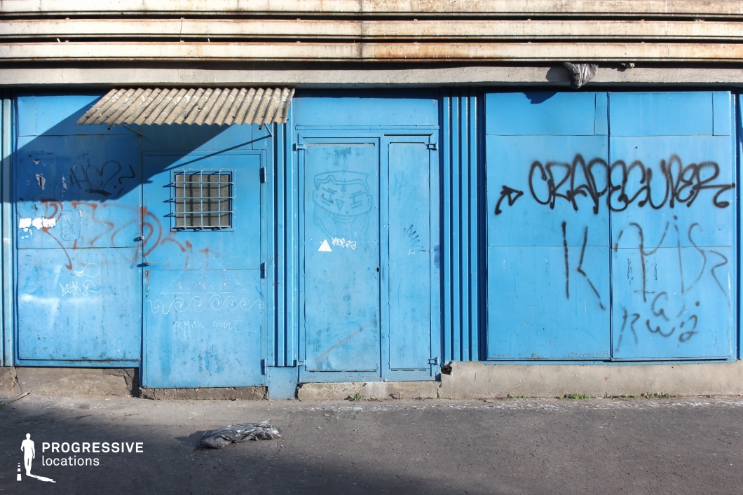 Blue metal industrial doors with textured concrete wall, photography and film location with bold color and simple geometry