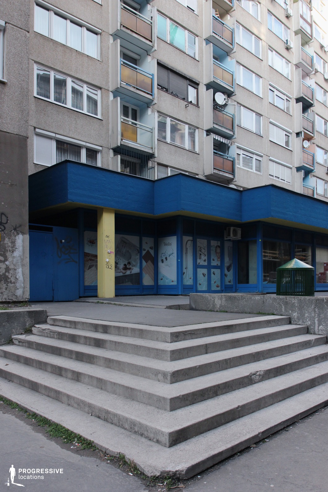 Tiered concrete steps leading to storefront under apartments, film and photography location with strong geometric entrance