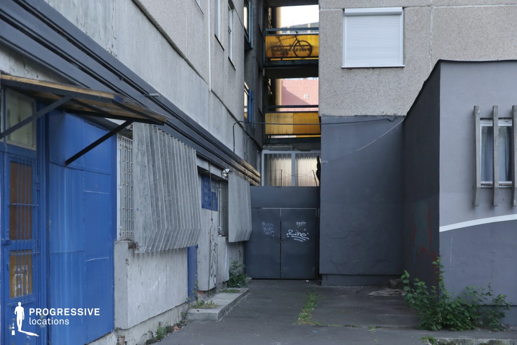 Narrow back alley with metal gate and residential walls, film and photography location with compressed urban perspective
