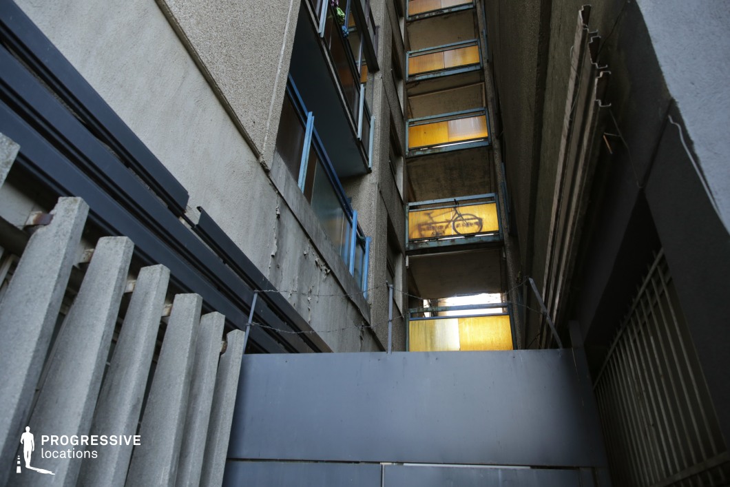 Tight urban passage with balconies and vertical walls, available for filming or photo shoots with strong upward perspective