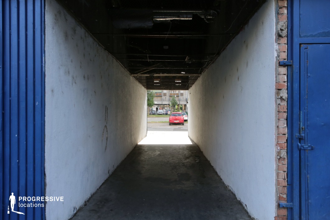 Narrow tunnel passage leading to open space, shooting location for film and photography projects with strong linear depth