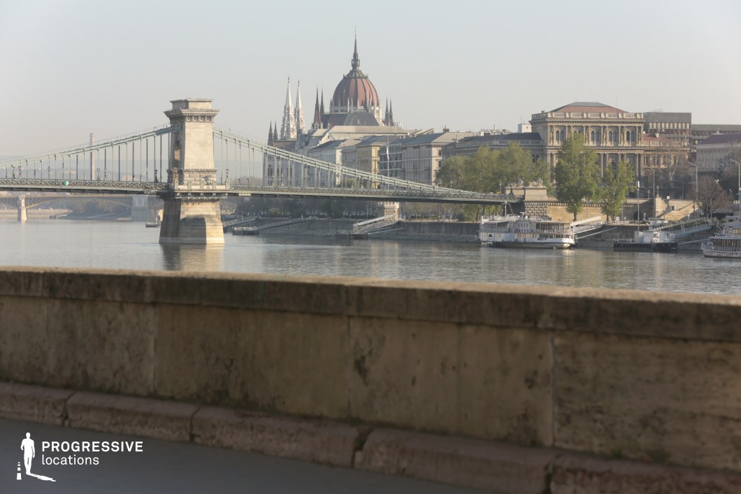 Suspension bridge over river with monumental building forms a film and photography location with layered urban composition