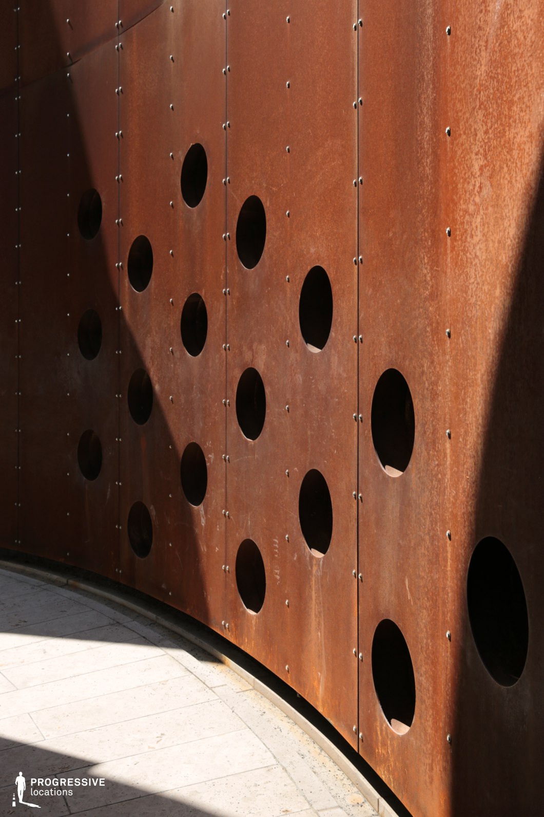 Curved perforated metal wall forms a photography and film location with industrial texture and geometric pattern