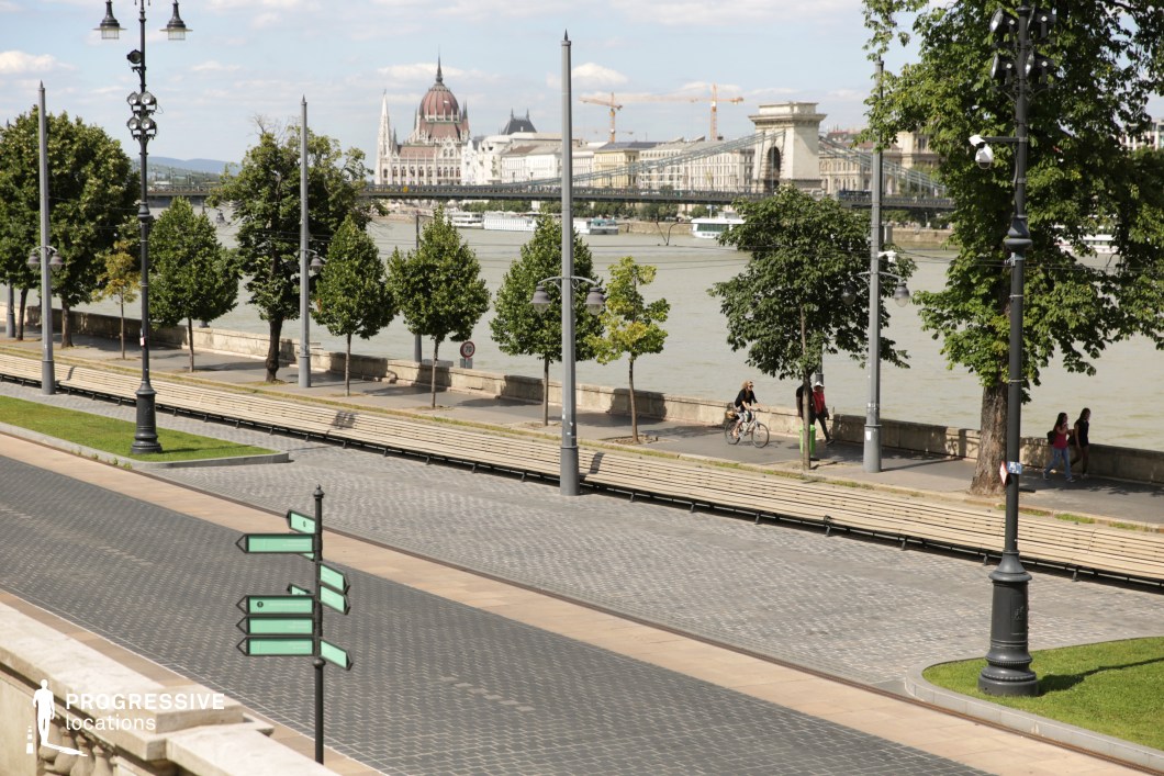 Tree-lined promenade along river as an ideal location for photography and filming with structured paths and bridge backdrop