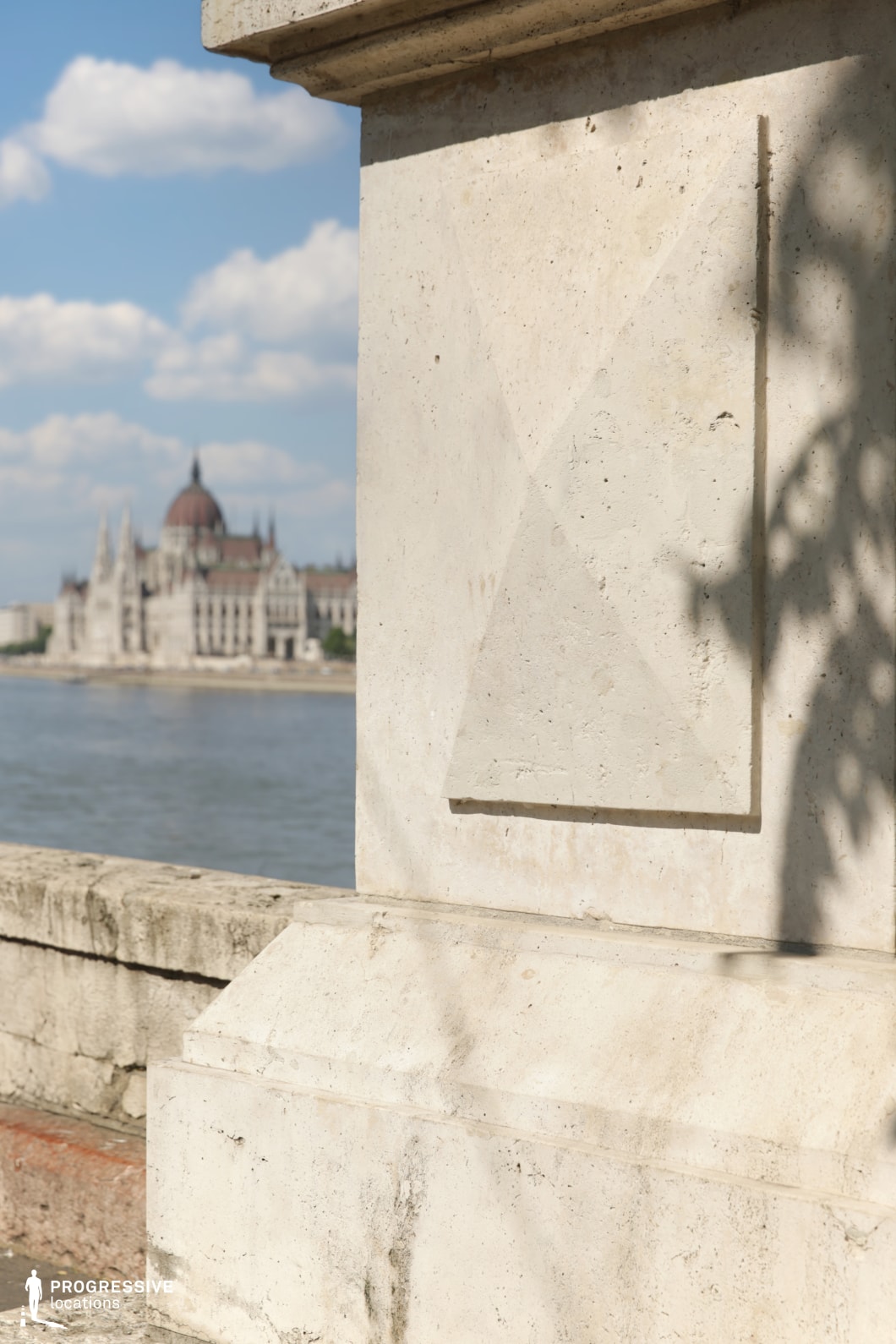 Stone wall foreground with river and architecture behind creates a photography and film location with strong depth layering
