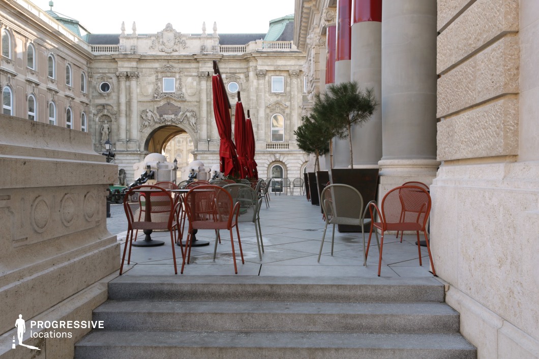 Outdoor terrace with seating beside historic facade, film and photography location with structured layout and architectural depth