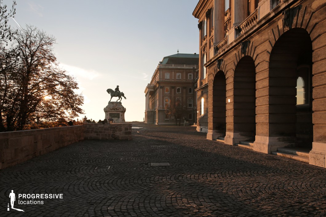 Cobblestone courtyard with arches and statue, shooting location for film and photography projects with strong architectural framing
