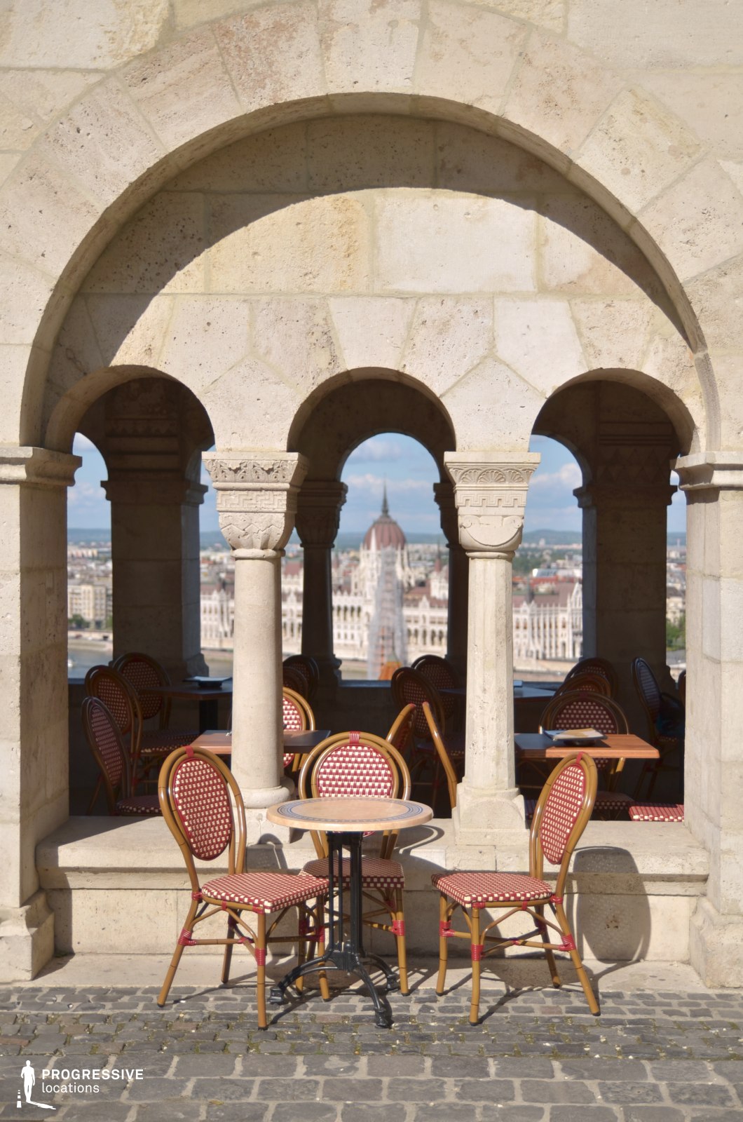 Café seating under stone arches, used for photo and film shoots with framed architectural openings and depth