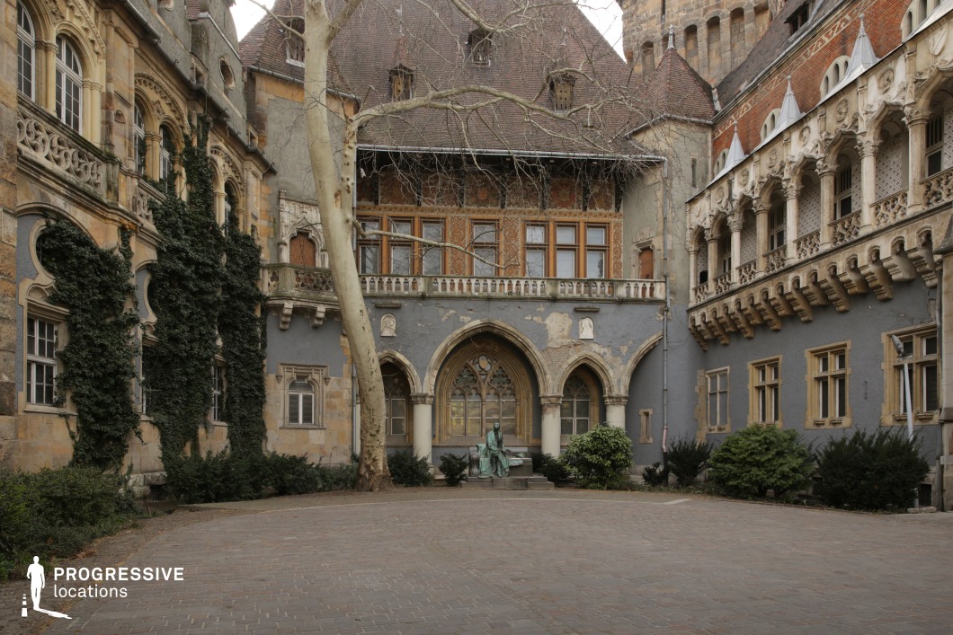 Enclosed historic courtyard with stone facades and arches, photography and film location with central open paved space